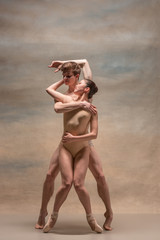 Couple of ballet dancers posing over gray background