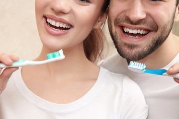 Young happy couple brushing teeth in bathroom