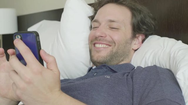 Man lying in bed looking at smart phone