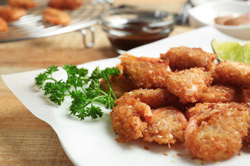 Plate with delicious coconut shrimps on table