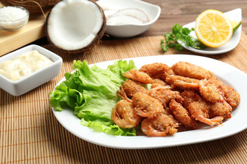 Plate with delicious coconut shrimps on table