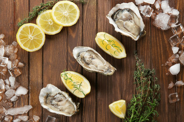 Tasty fresh oysters with sliced juicy lemon and ice on wooden background. Aphrodisiac food for increasing sexual desire