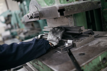 Metallurgy heavy industry. Factory for production of heavy pellet stoves and boilers. Worker hands close up. Extremely dark conditions and visible noise. Focus on foreground.