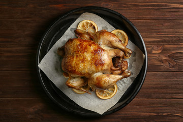 Homemade baked chicken with lemon on wooden table