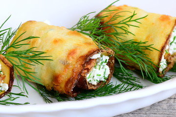 Homemade zucchini rolls idea. Stuffed zucchini rolls stuffed with creamy cottage cheese filling and herbs on a plate. Diet appetizer recipe. Closeup