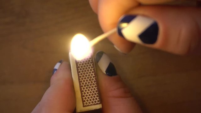 female hand lighting a match on a matchbox.