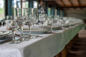 Interior of the restaurant, cafe. Tables with dishes, plates, woks, knives, glasses and glasses, preparation for the celebration. Horizontal frame