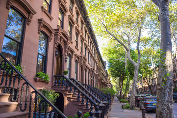 Scenic view of a classic Brooklyn brownstone block with a long facade and ornate stoop balustrades...