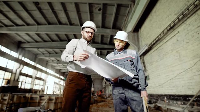 The foreman explains to the worker the possibility of making a change to the building site, where the old factory is being modified