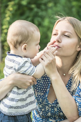 Young woman kissing the small fingers of her baby son
