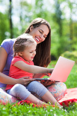 Mother with child using laptop outdoors
