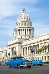 Poster Felgekleurde klassieke Amerikaanse auto& 39 s die dienst doen als taxi& 39 s passeren de hoofdstraat voor het Capitolio-gebouw in Centraal Havana, Cuba © lazyllama