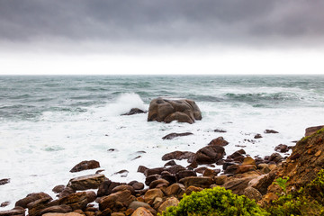 A wave from the Atlantic ocean crashes on a large boulder, Cape Town, South Africa.