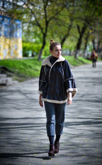 Beautiful female model wearing stylish leather poncho and tweed trousers walking around the hidden places of a European city, having fun.