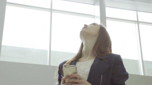 Woman using smartphone while waiting in lobby