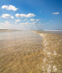 In Florida, a small wave washes over a large shallow sand bar on sunny day