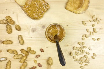 Peanut butter on a slice of bread in wooden background - top view