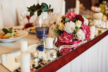 Bouquet of red and white roses stands on table with pearls