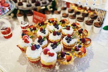 Cupcakes with white cream and berries served on glass dish