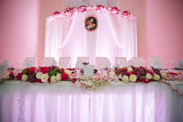 Pink flowers decorate white dinner table for newlyweds
