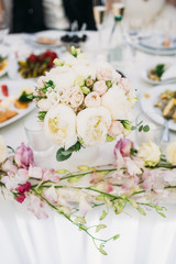 Bouquet of white peonies stands on a dinner table