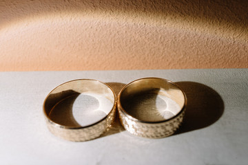 Golden wedding rings lie on white shelf