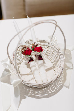 White candles with red boutonnieres lie in the basket