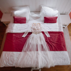 Wedding dress lies on red bed