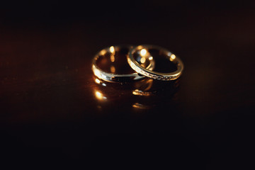 Golden wedding rings lie on wooden table