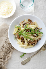 Italian Pasta with mushrooms, arugula and parmesan in white bowl