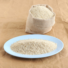 Healthy food brown top millet in a tray and in the background is the sack with the same millet.