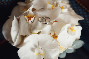 Fototapeta na wymiar Golden wedding rings lie on white orchids