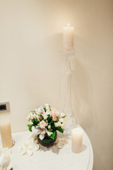 White candle stands on table with little bouquet