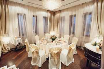 White dinner table with flowers stands in the corner of the restaurant