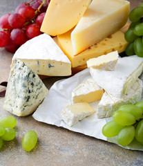 Various types of fresh Cheese with grapes on slate