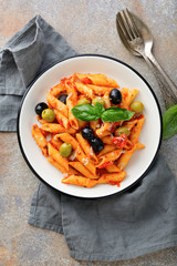 Pasta Penne in tomato sauce with olive on a slate background