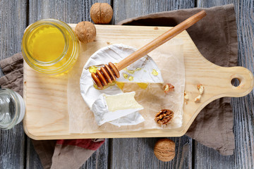 Brie cheese with honey and walnuts on a cutting board