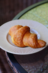 Croissant in white plate on a round glass table
