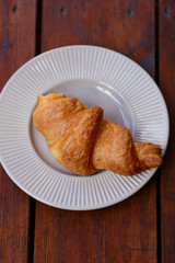 Croissant in white plate on a wooden boards