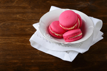 Sweet strawberry macaroon in a plate on wooden background