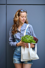 Young stylish woman is holding in their hands a linen Bag with Lettuce Salad
