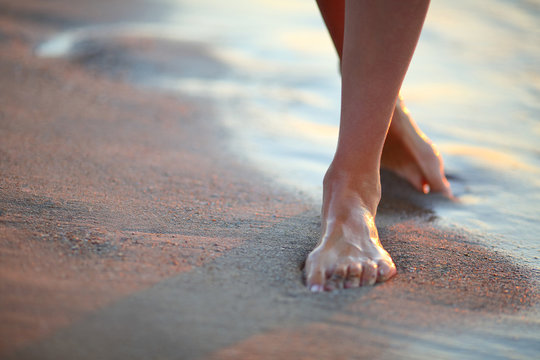 Beautiful woman legs on the beach at sunrise