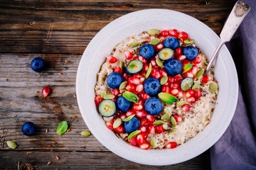 Healthy breakfast bowl oatmeal with fresh blueberries, pomegranate, mint, chia, flax and pumpkin seeds