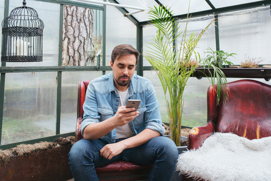 Man using smartphone in hothouse