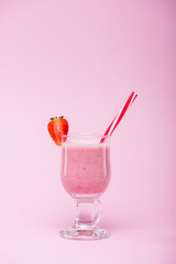 delicious strawberry milkshake in glass with straw and fresh strawberry isolated on pink