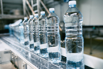 Bottling plant - Water bottling line for processing and bottling pure spring water into small blue bottles. Selective focus. 