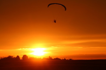 Motorized paraglider on sunset background