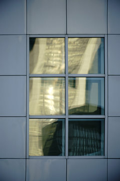 Blechfassade mit abstrakten Fenstern  / Abstrakte Spiegelungen in quadratischen Fenstern an einer markanten Fassade aus Blechplatten.