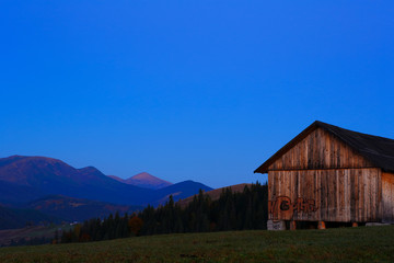 Fototapeta na wymiar Wooden barn with graffiti in the background morning mountain