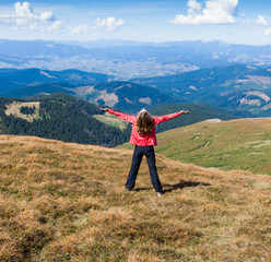 Woman tourist on the mountain with raised hands feeling success